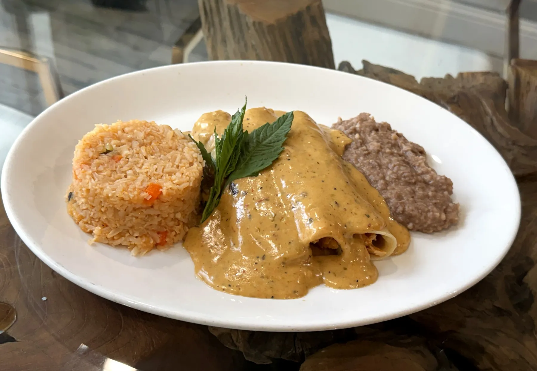 Enchiladas Poblanas in poblano cream sauce with Mexican rice and refried beans