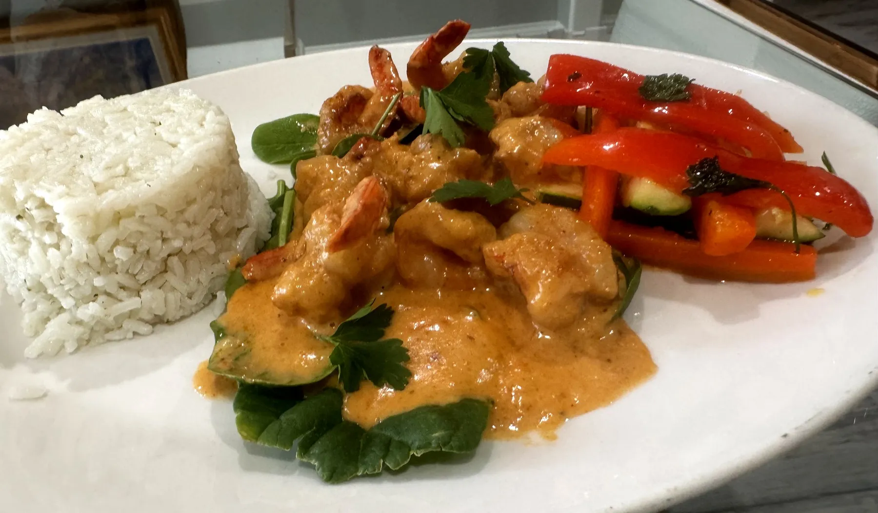 Sautéed shrimp in a creamy sauce over spinach with white rice and grilled peppers