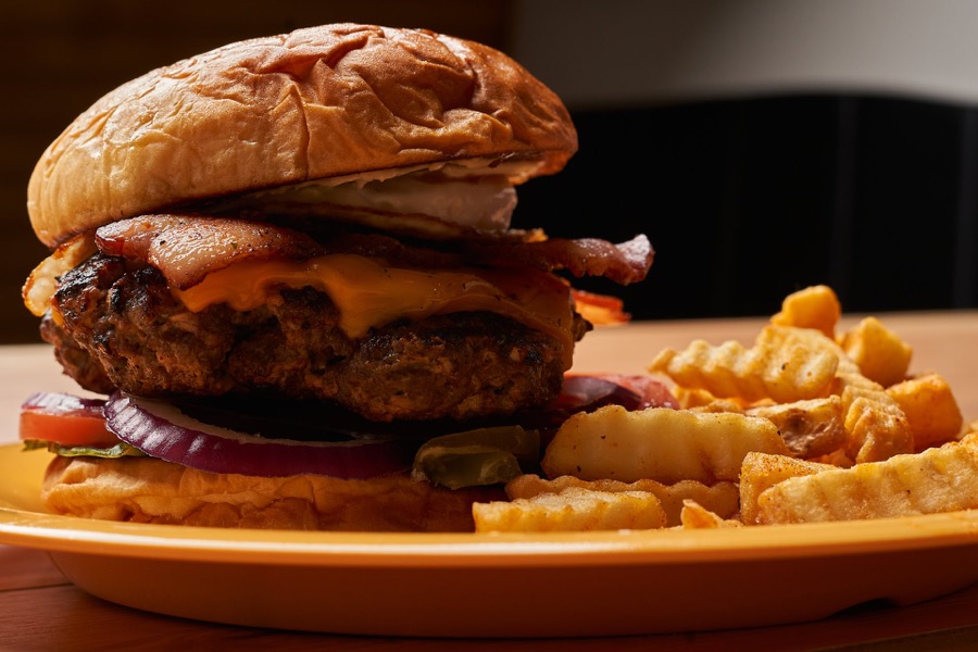 Brunch cheeseburger stacked with bacon next to crinkle fries
