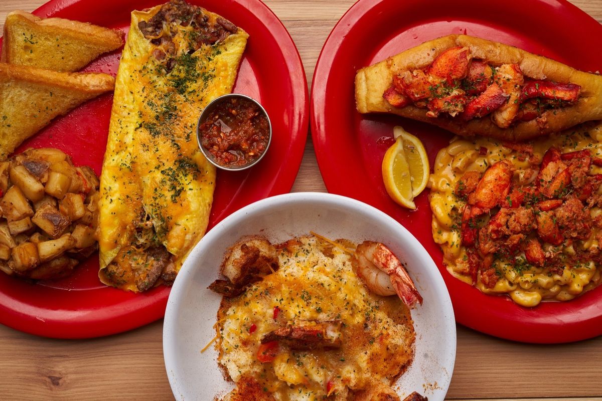 A catering spread of omelettes, lobster rolls, and shrimp and grits on red plates