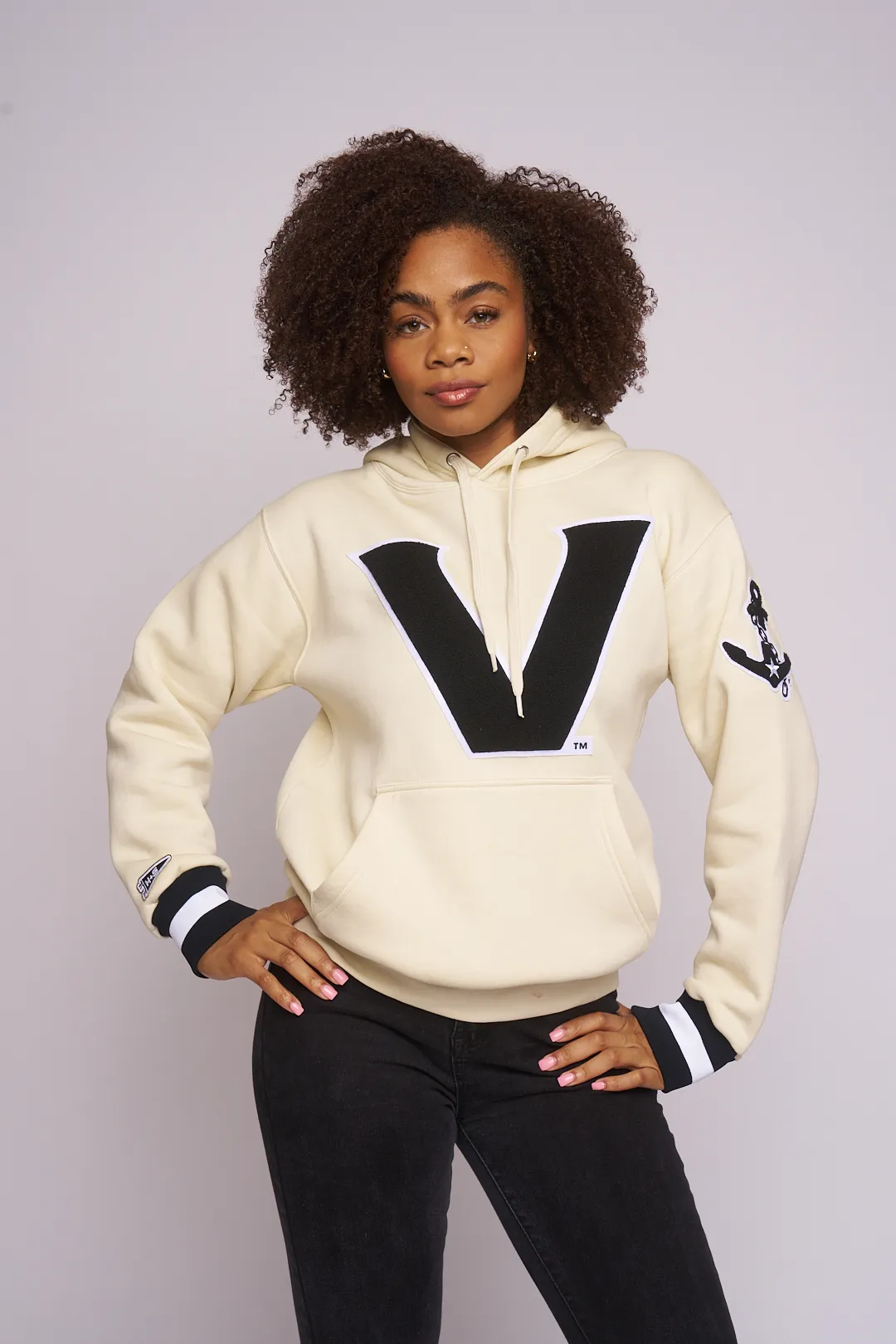 Model in the cream Vanderbilt V hoodie, hands on hips