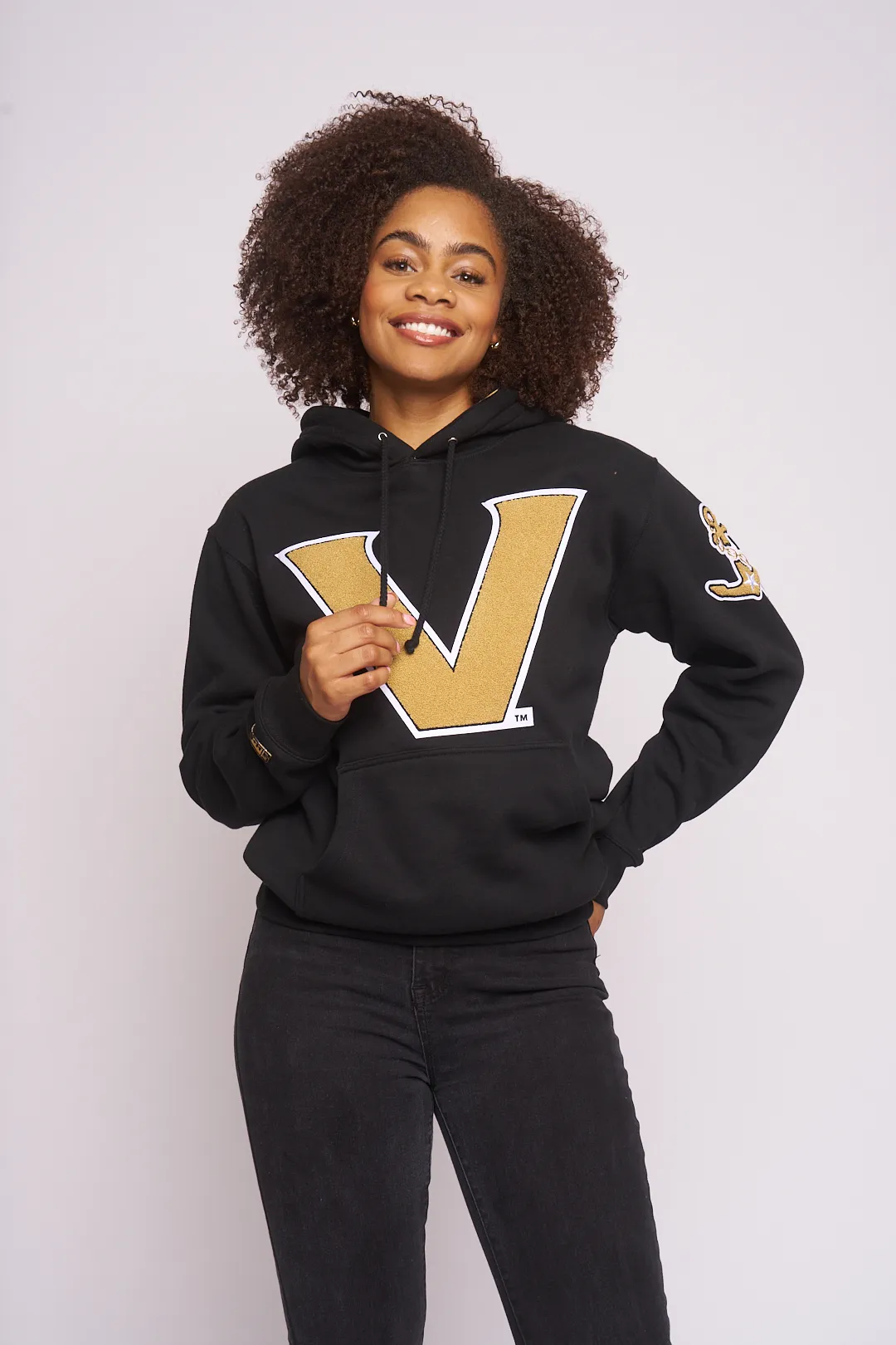 Smiling model in the black and gold Vanderbilt V hoodie